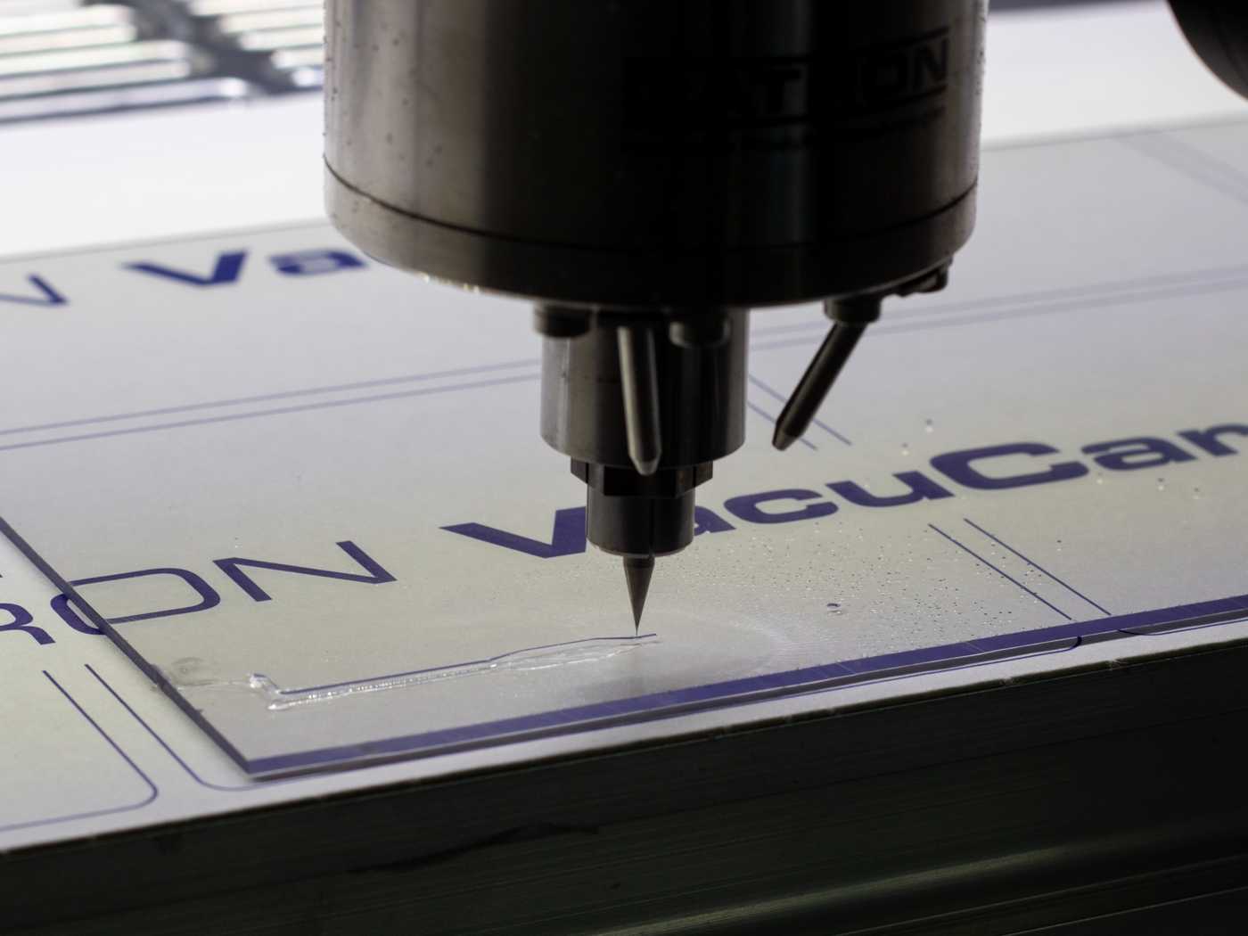 A CNC machine milling a microfluidic device. The tiny end mill traces the outline of a small feature on the device.