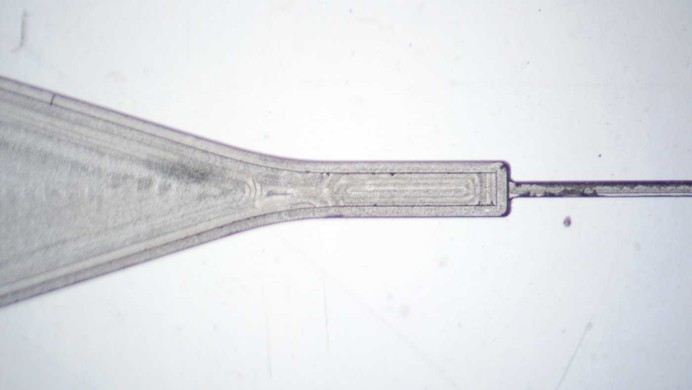 Close-up of a micromilled capillary valve and sloped microfluidic channel. The surfaces are somewhat smooth with clearly visible tool marks.