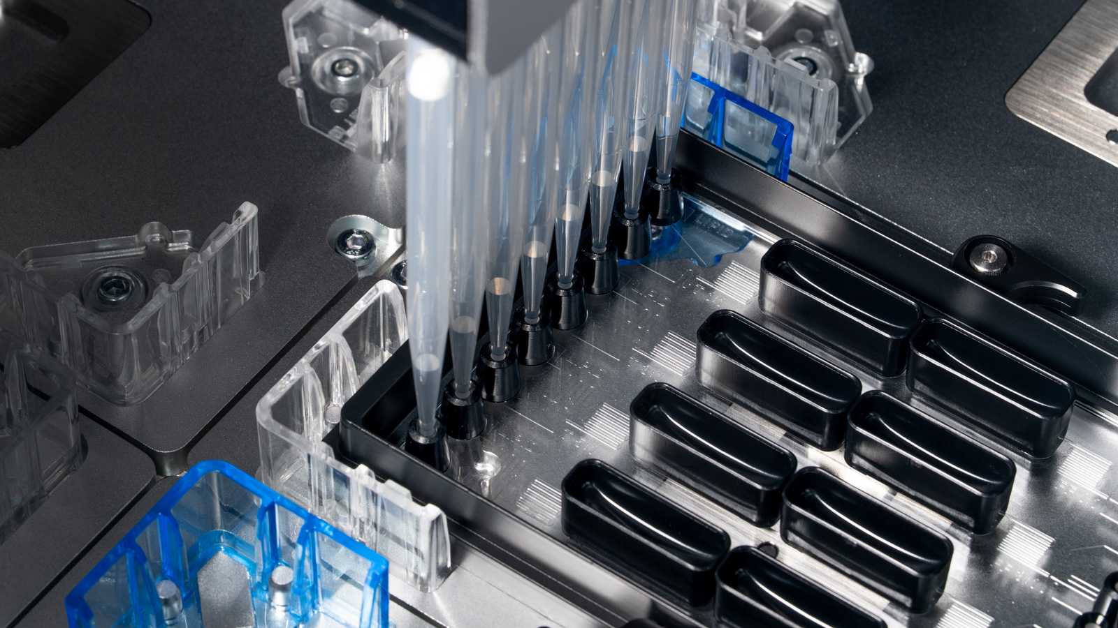 Eight pipette tips engaging with a SLAS format microfluidic device on the deck of a liquid handler.