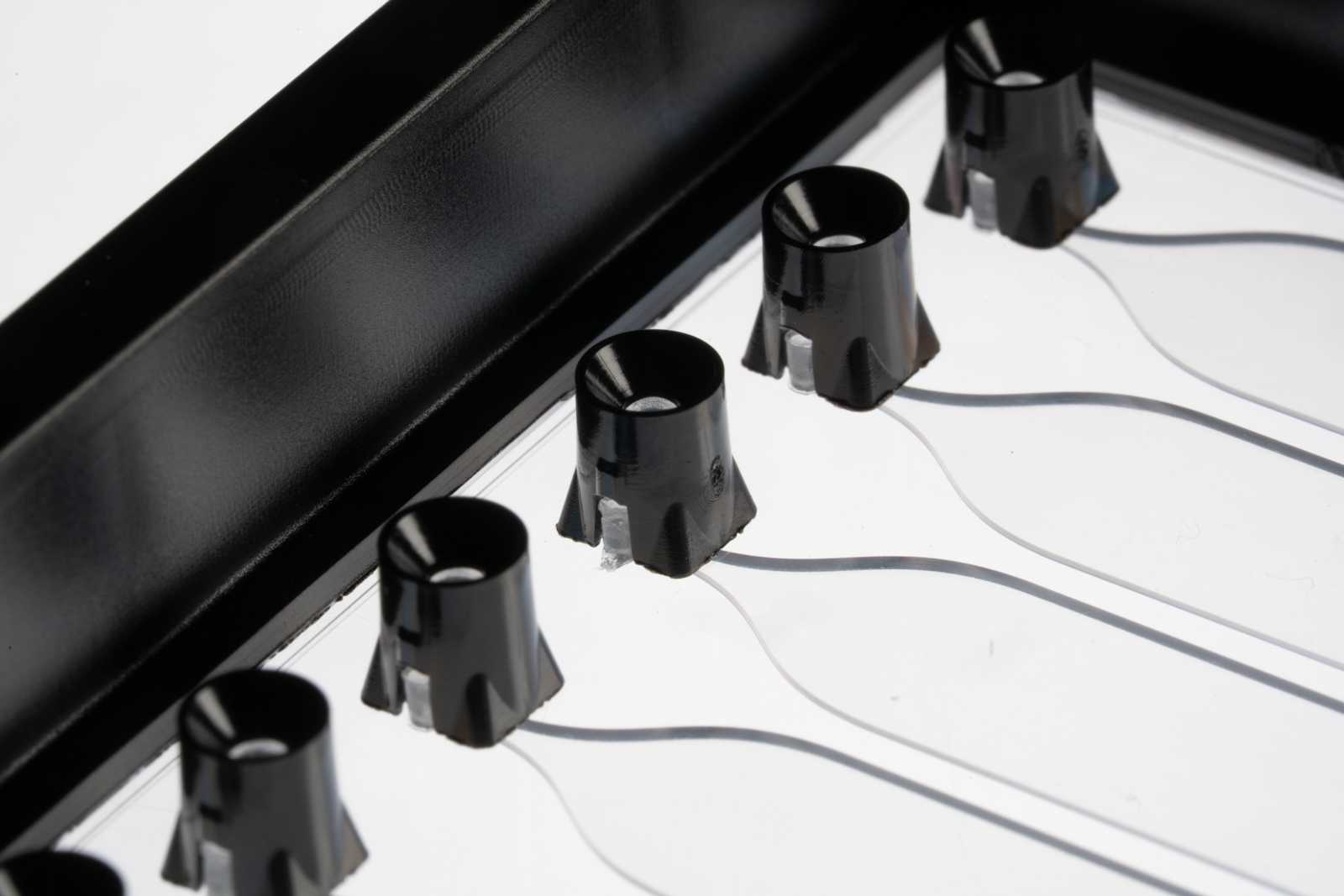 A row of pipette interfaces on a SLAS format microfluidic device, each connected to a channel.